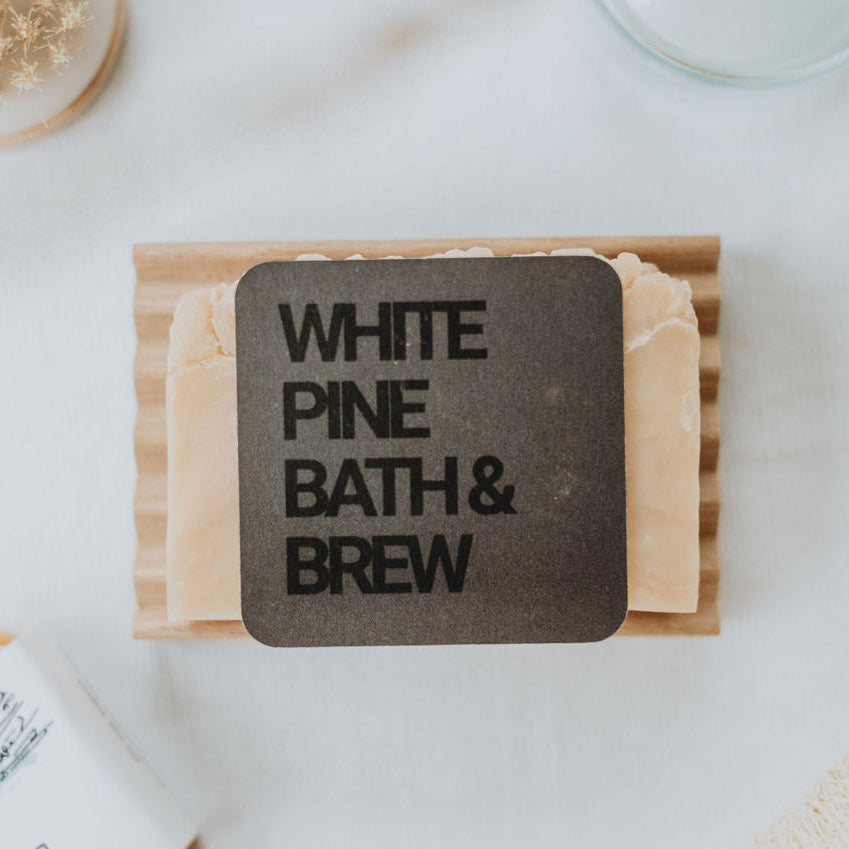 white pine bath + Brew gift card resting on a bar of soap