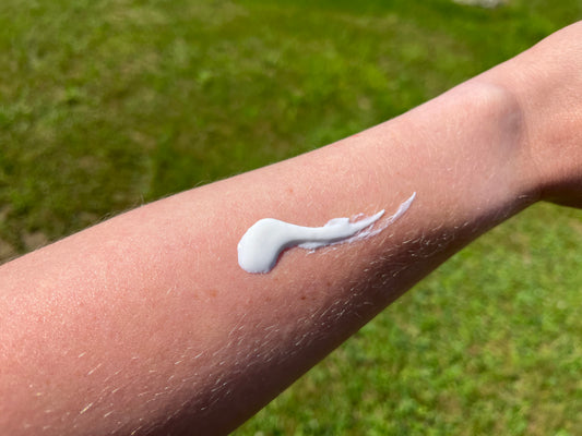 mineral sunscreen on forearm with green summer grass in background