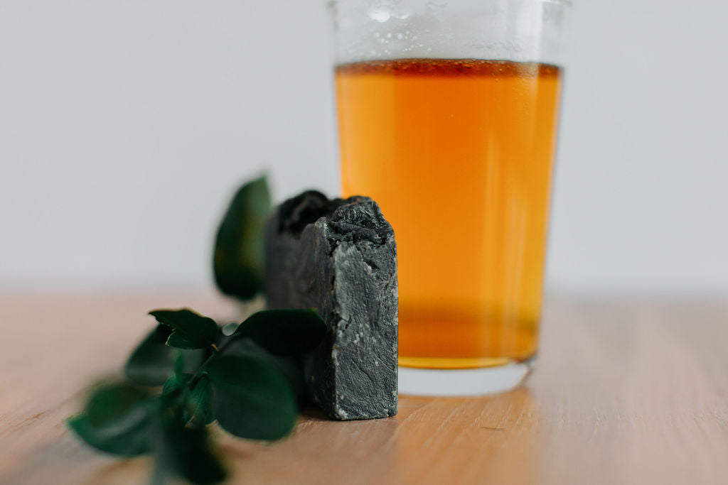 charcoal beer soap next to a glass of amber ale