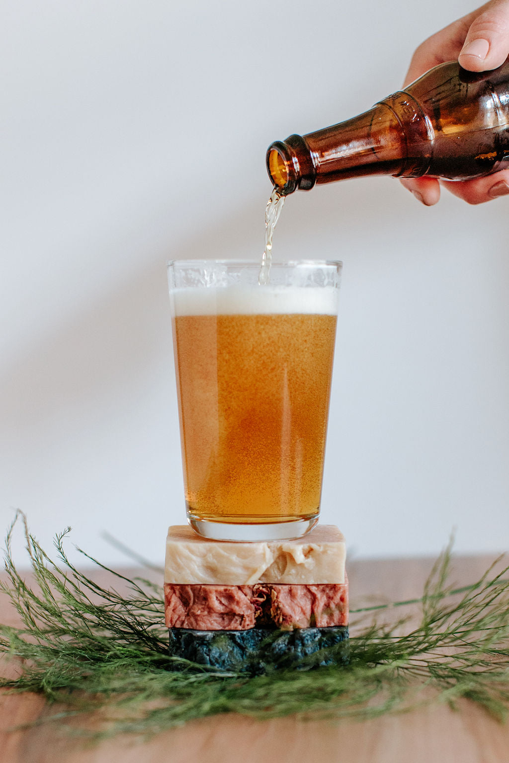 bottle of beer being poured into a glass sitting on a stack of three beer soaps
