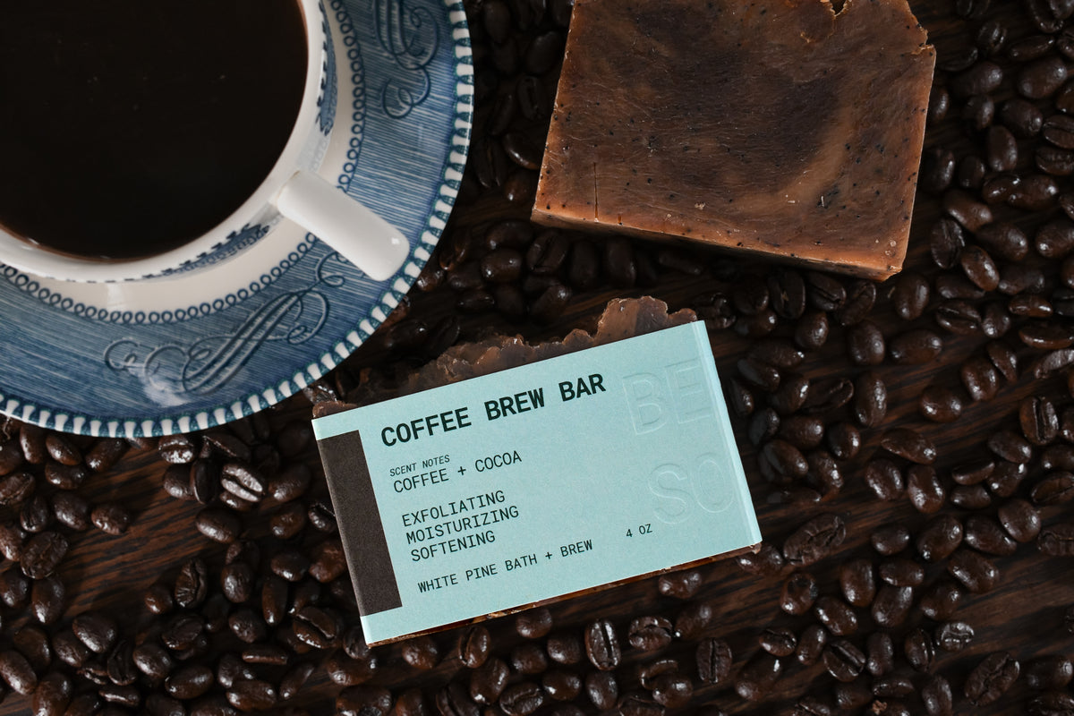 coffee brew bar beer soap on a bed of roasted coffee beans near a cup of coffee