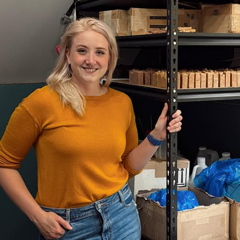 Elaine Kinney standing next to a storage rack with boxes and supplies in a warehouse setting